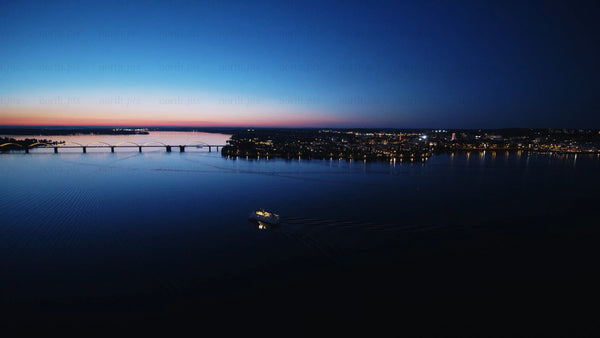 Aerial view of Luleå at sunset with boat, bridge, and city Lights