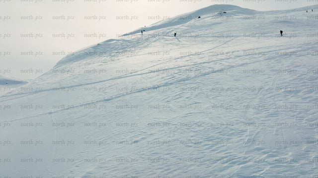 Skiers and snowboarders ascend snowy mountain at Riksgränsen ski resort