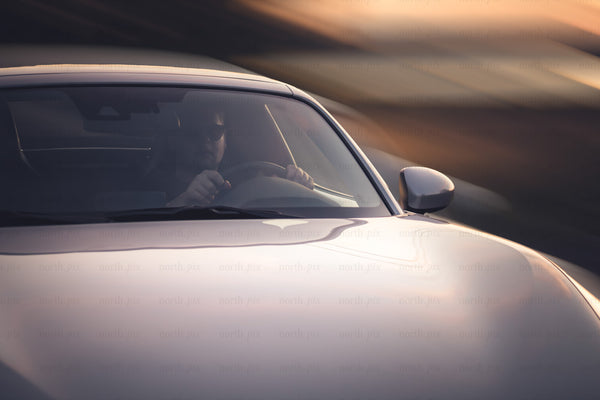Driver in sports car at sunset