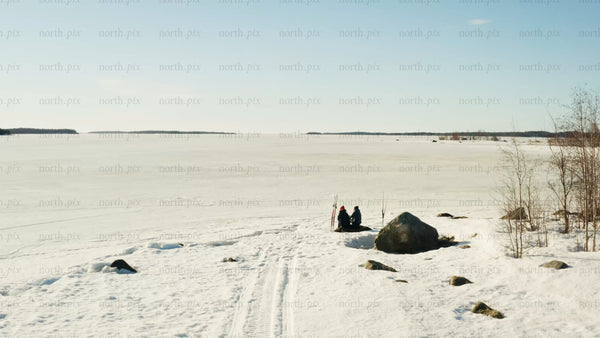 Winter day in Luleå: Two people by a frozen lake - drone shot