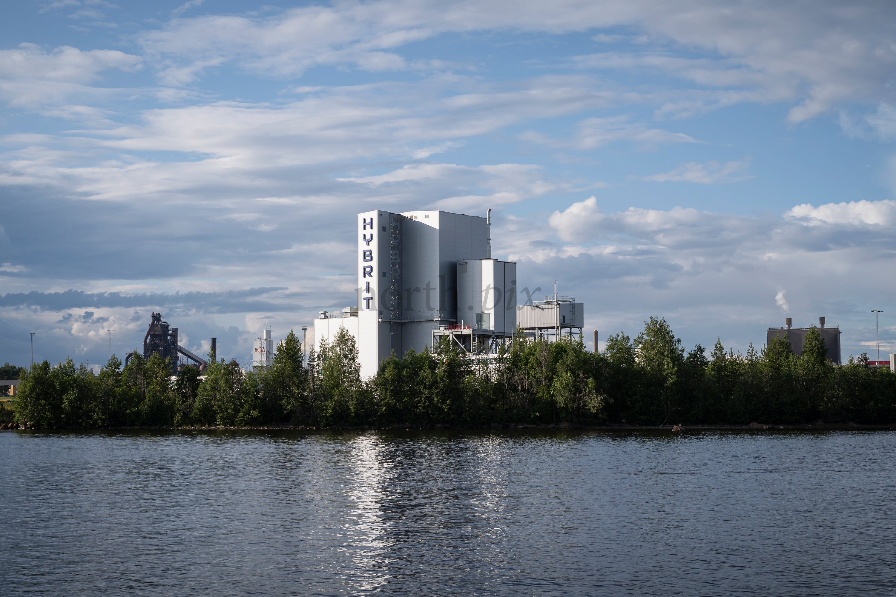 Industrial plant with HYBRIT signage by river in daytime