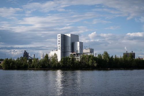 Industrial plant with HYBRIT signage by river in daytime