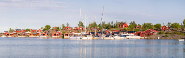 Red boathouses and yachts on archipelago coast, summer morning