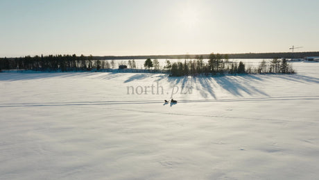 Snowmobile and Sled Across a Snowy Landscape in Luleå, Sweden, During Sunny Winter Day