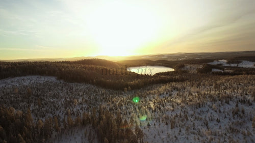 Vintersolnedgång över frusen sjö och snötäckt skog i Gunnarsbyn, Sverige
