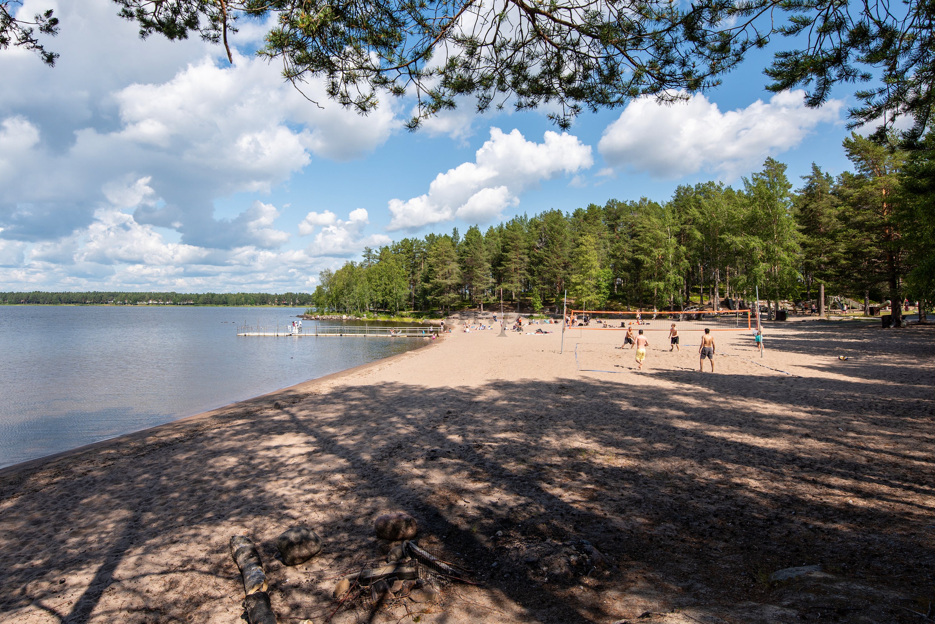 People playing volleyball on a sandy lake beach in summer