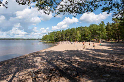 People playing volleyball on a sandy lake beach in summer