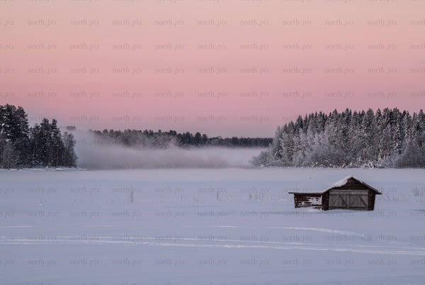 Boathouse on a frozen lake at sunrise