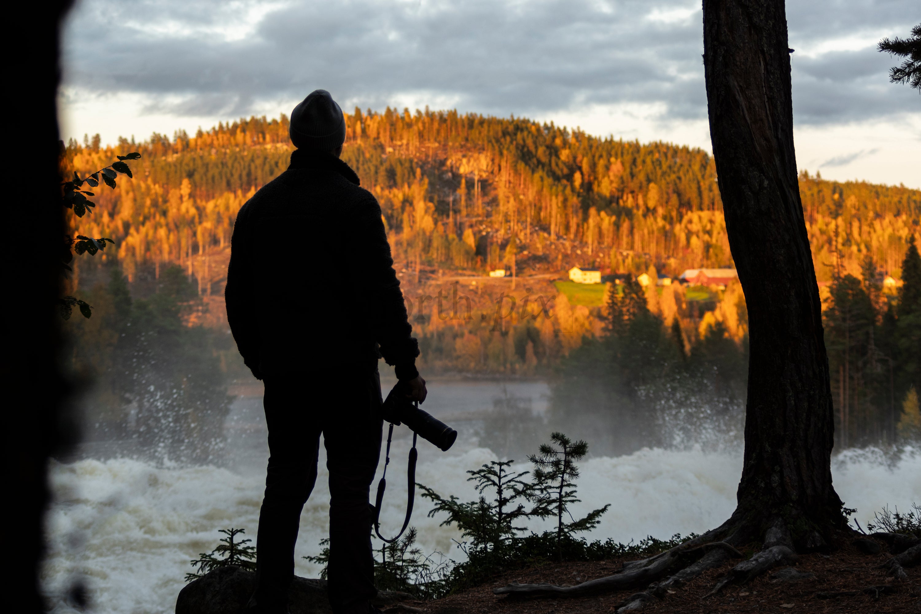 Photographer at riverside rapids at sunset, autumn