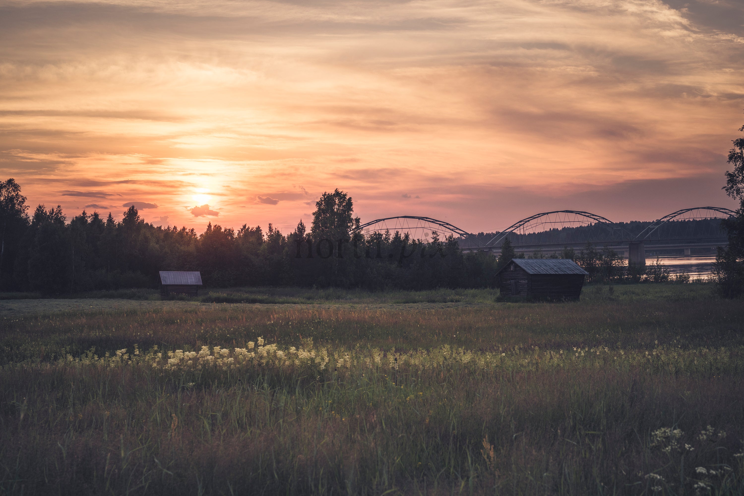 Sunset over meadow with Gäddvik bridge and wooden huts