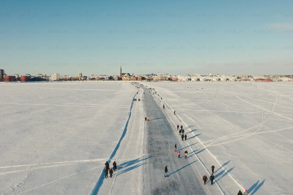 Snowy Luleå city center aerial view of frozen lake path and people walking