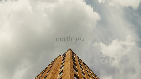 Low Angle View of Brick Apartment Building With Slow Upward Camera Movement and Cloudy Sky
