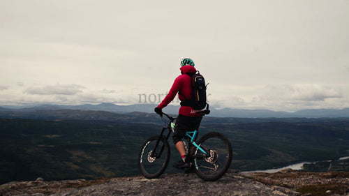 Mountainbiker på toppen innan utförsåkning - naturskön dalutsikt