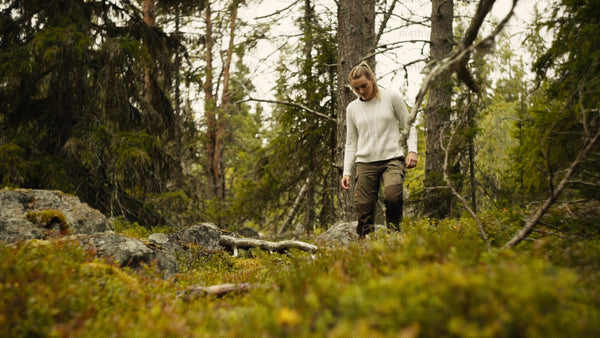 Woman picking berries in Luleå archipelago forest on a cloudy summer day