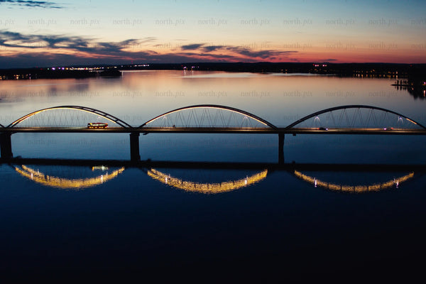 Sunset over modern arch bridges in Luleå city center with reflective calm water