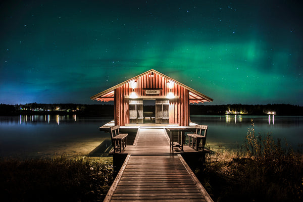 Wooden boathouse sjöbodan on lake dock under Aurora