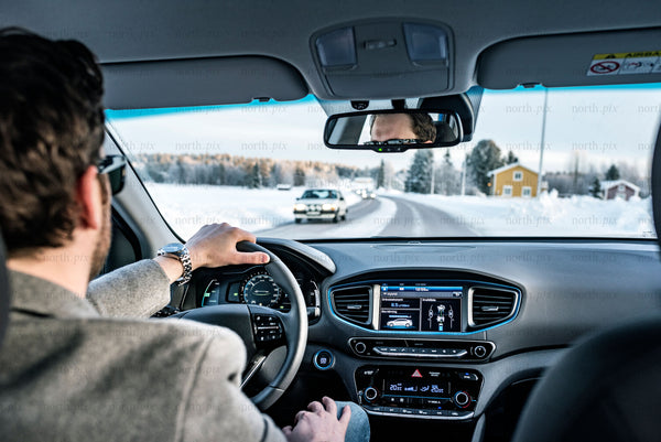 Man driving car on snowy country road during daytime