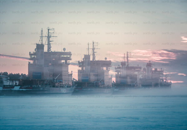 Icebreakers moored in icy harbor at sunrise