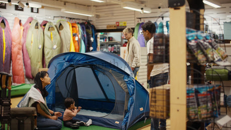 Family Choosing a Tent in a Camping Store with Salesman Assistance