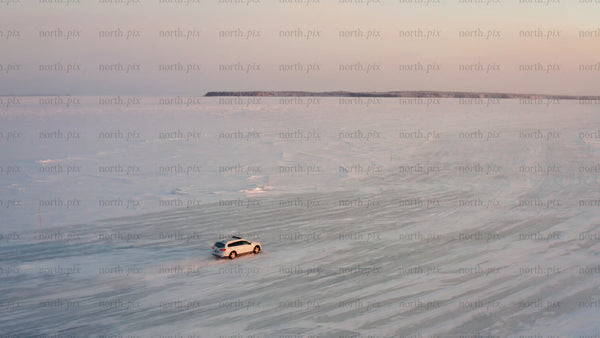 Driving on a frozen ice road in the Luleå archipelago at sunset