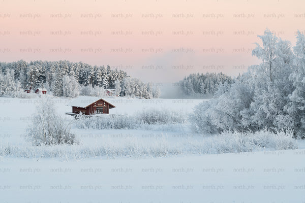 Red boathouse on a frozen lake at dawn