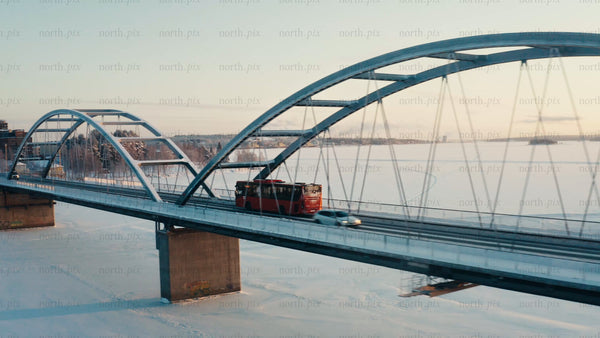 Winter sunrise over frozen Luleå: Aerial view of bridge with traffic
