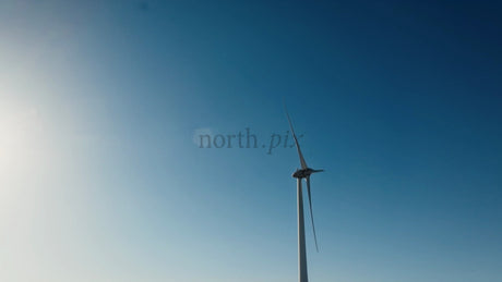 Wind Turbine Rotating Against Blue Sky With Sun, Low Angle View in Winter