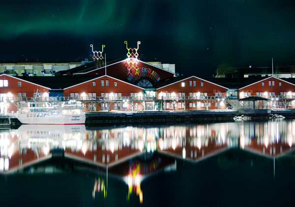 Norrbottensteatern red waterfront building under Aurora