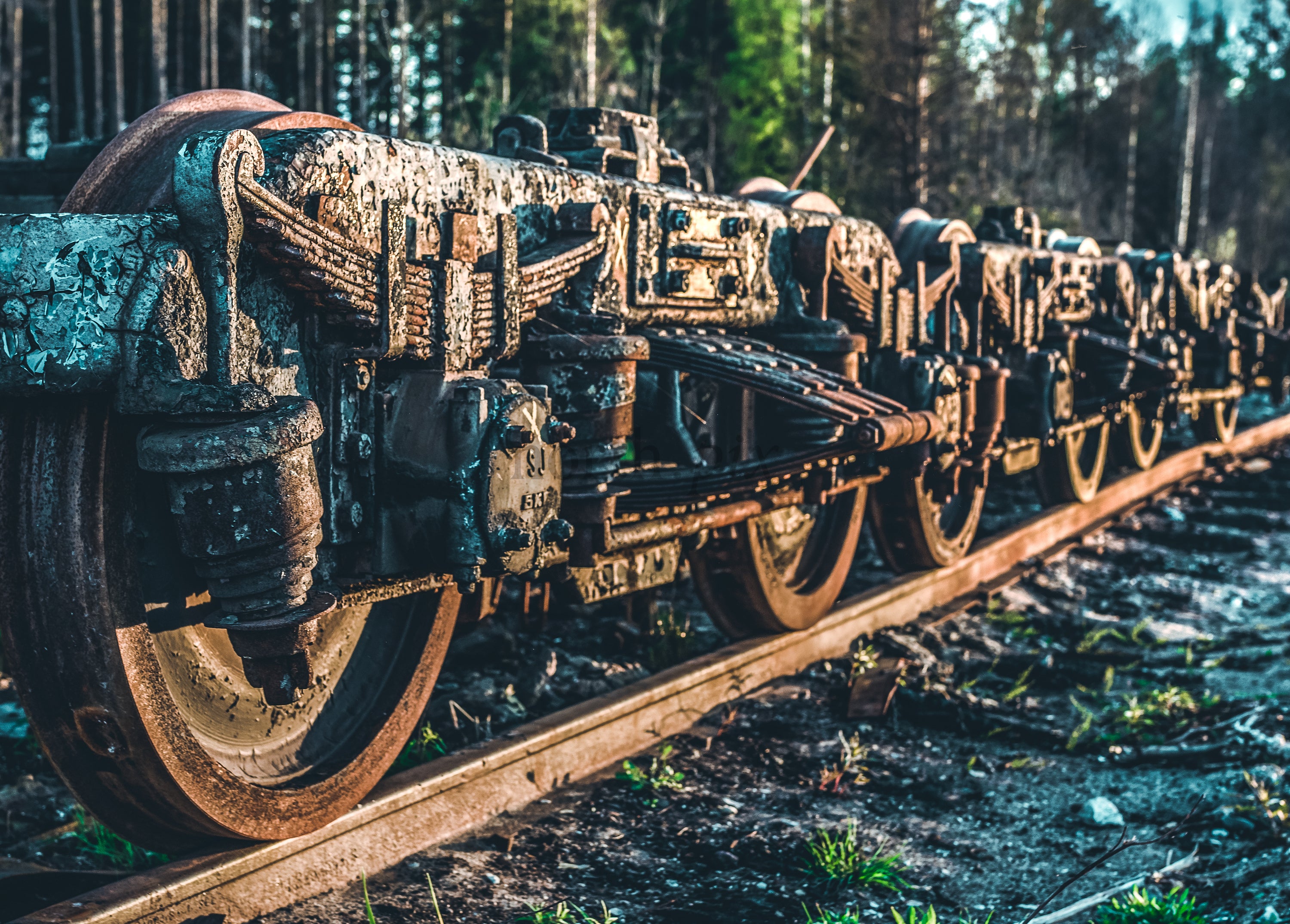 Close-up of rusty train bogie wheels on rails at sunrise