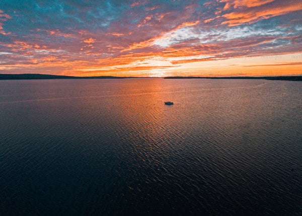Drone shot of a sunset over wide calm lake scene