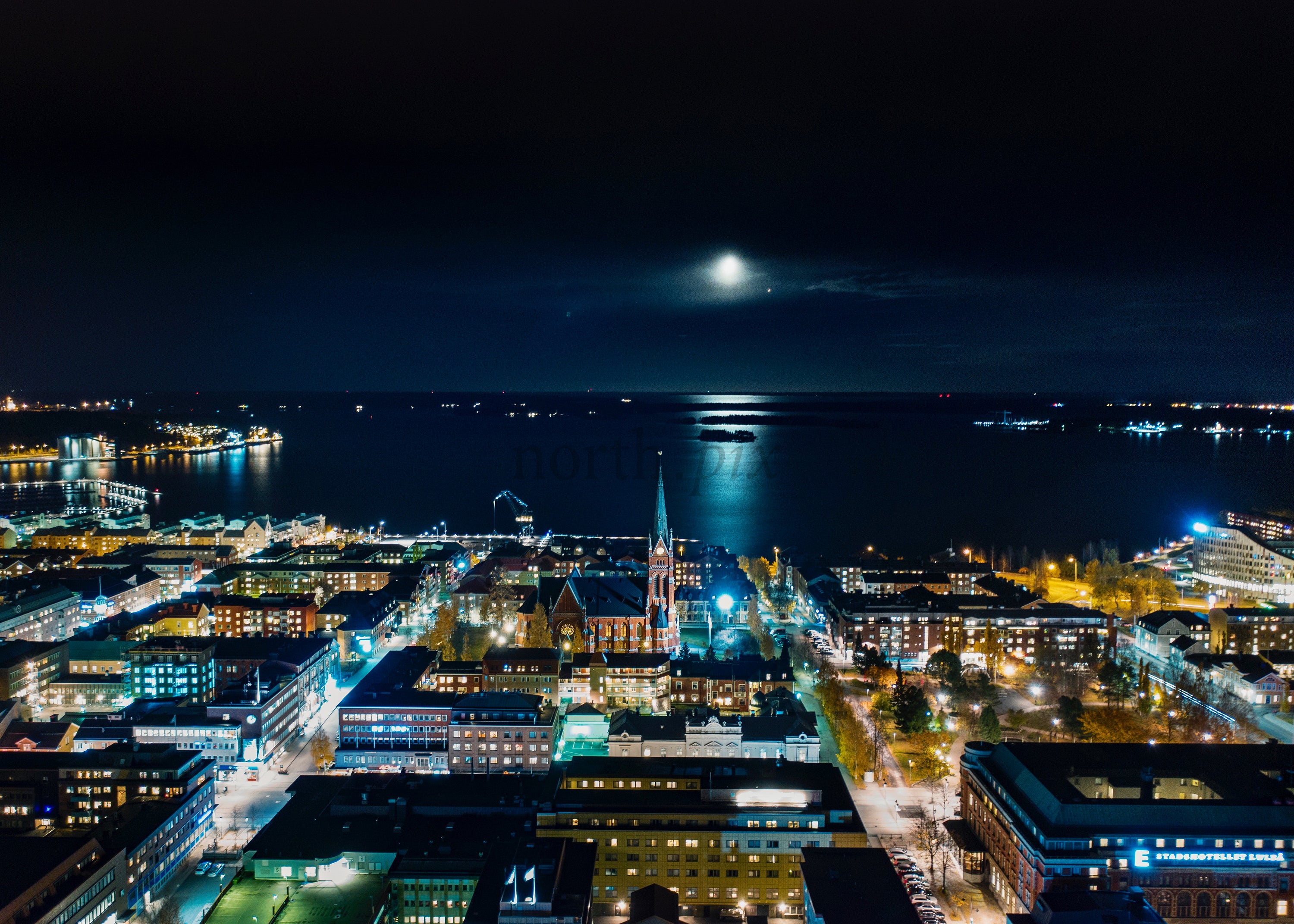Nighttime Aerial View of Lulea Cityscape with Moonlit Bay