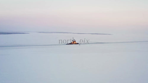 Isbrytare navigerar i frusna vatten i Luleå skärgård vid solnedgången