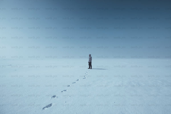 Person standing on a snowy plain under clear sky
