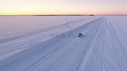 Körning på is: Flygfoto över bil på snötäckt vinterväg i Luleå skärgård vid solnedgången