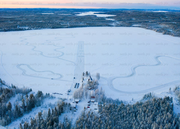 Aerial view of frozen lake and winter forest during sunrise