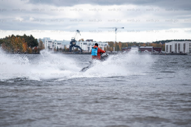 Person riding jet ski near harbor in autumn