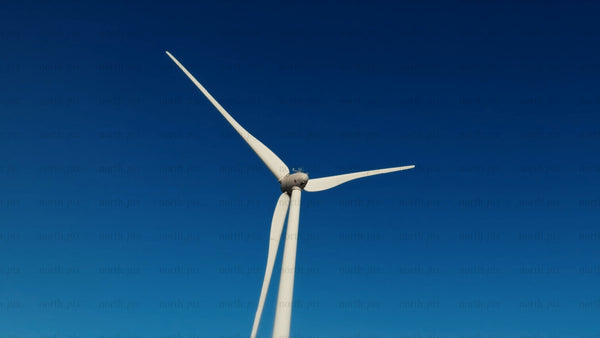 Wind turbine rotating against a clear blue sky in a winter landscape
