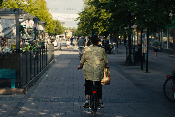 Cyclist riding through Luleå city center with outdoor cafes and busy pedestrian street