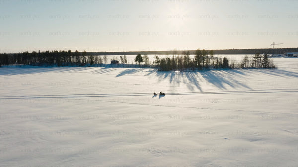 Snowmobile and sled across a snowy landscape in Luleå, during sunny winter day