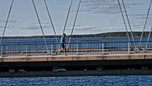 Man running across Bergnäsbron bridge in Luleå, on a sunny summer day