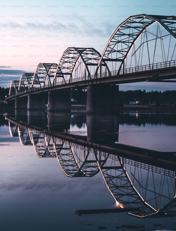 Arched steel bridge with reflection at dusk
