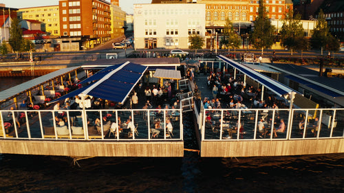 Luleå, Sverige: Sommarsolnedgång över hamnen med människor som njuter av drinkar på flytande restaurang