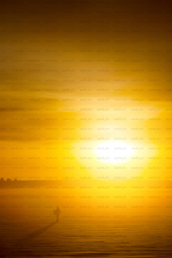 Man silhouette walking on frozen lake at sunrise