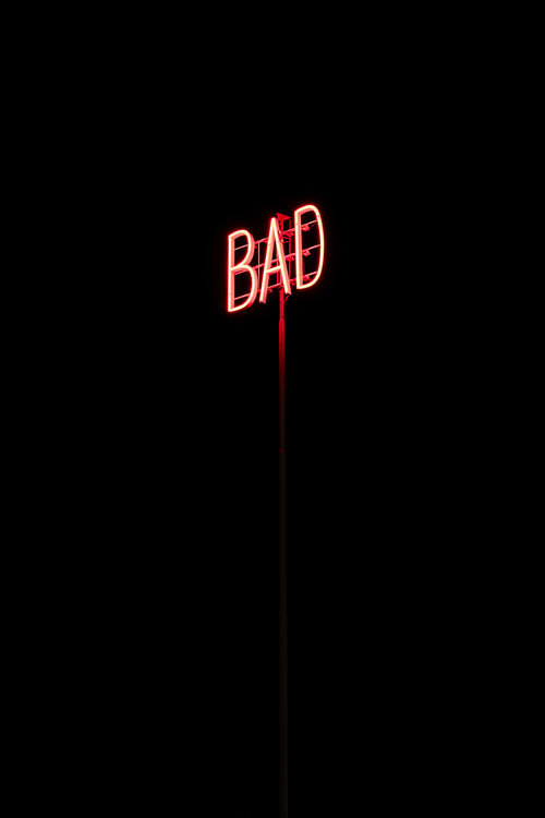 Röd neonskylt med texten BAD på stolpe under natten
