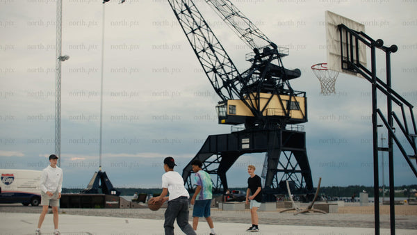 Friends playing basketball in urban Luleå at sunset, capturing summer fun and activity