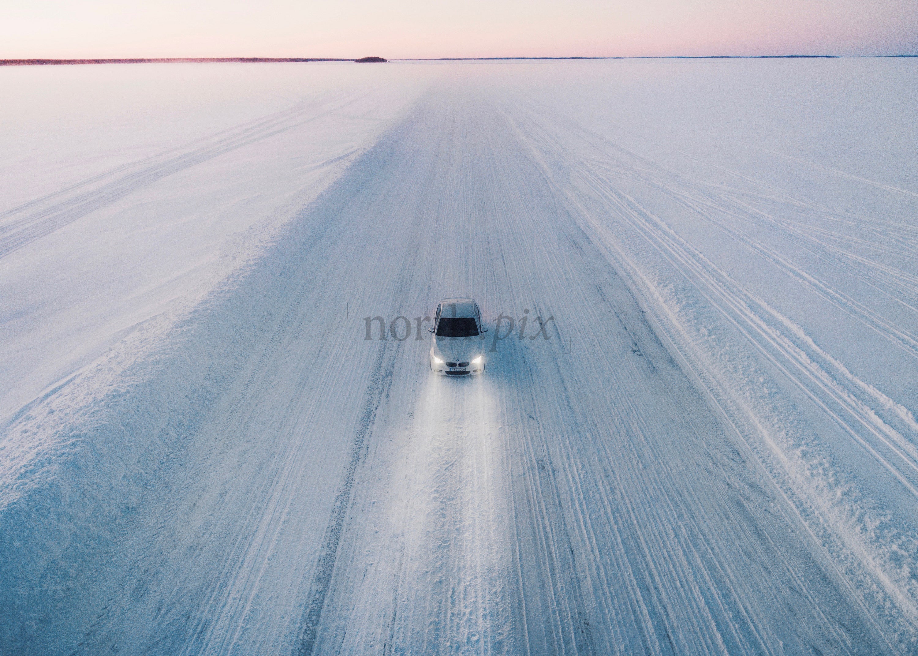White Car Driving on a Snowy Ice Road During Sunset in Winter