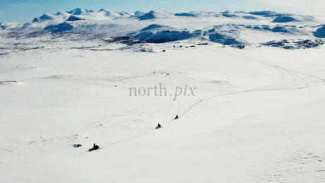 Snowmobiles Riding Across Snowy Landscape with Majestic Mountains