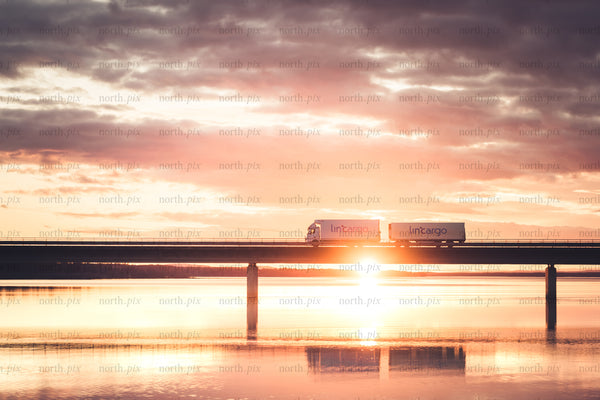Cargo trucks on bridge at sunrise