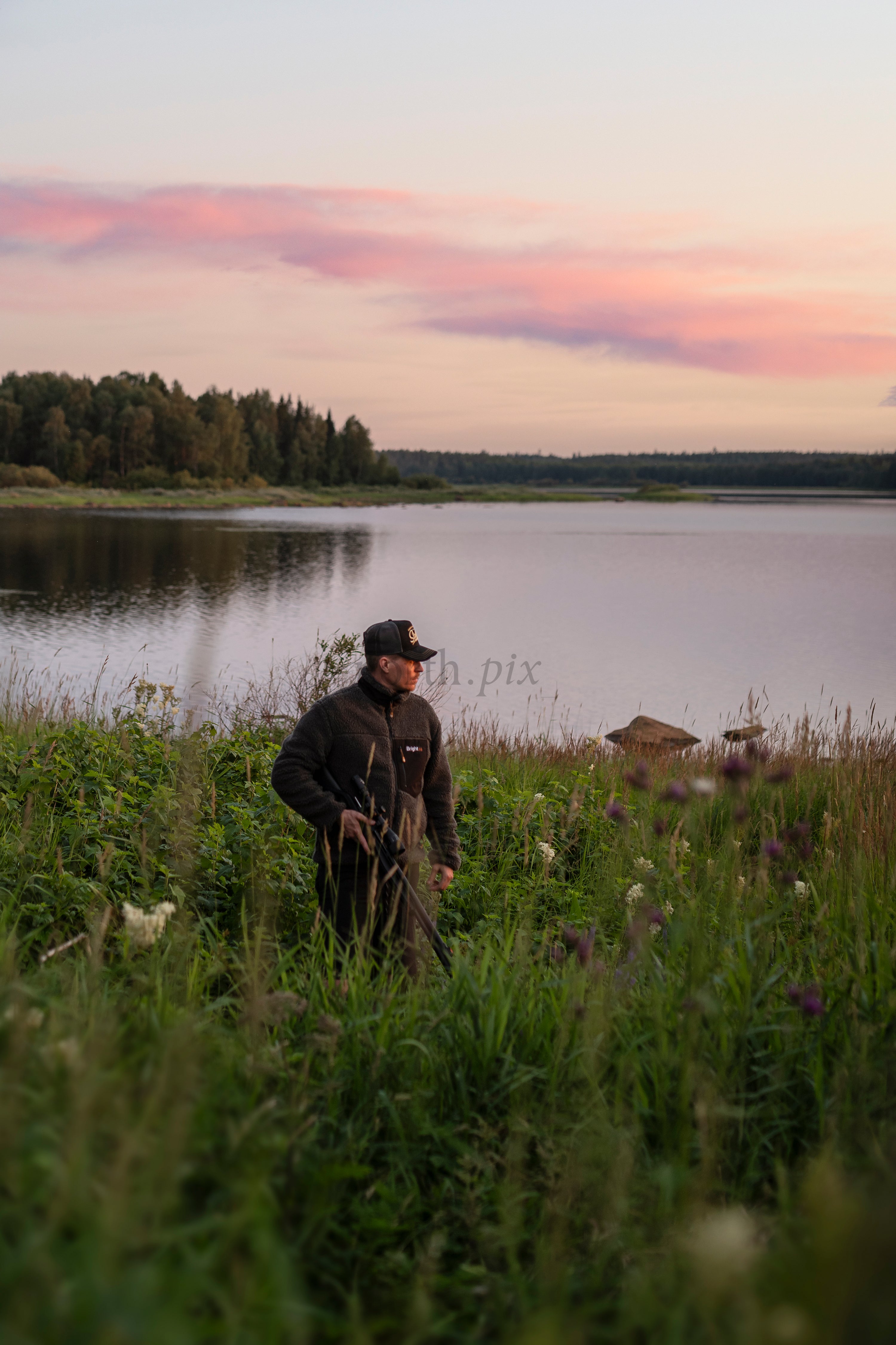 Man standing by lake at sunset in summer