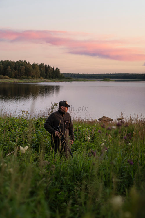 Man standing by lake at sunset in summer